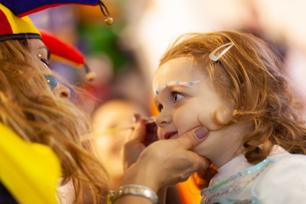 Face painter painting child's face at party